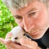 Breeder holding Chico Short Hair Chihuahua in a red flower garden