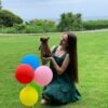 Nanny holding Choco chocolate long coat Chihuahua puppy in large green yard