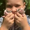 Brandon holding newborn Maya and Merribeth Teacup Chihuahua puppies close to his face with a loving smile