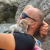 Pretty Penny Teacup Chihuahua perched on a large rock beside Uncle Mark near the river.